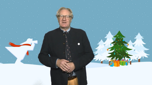 Der Rektor steht vor einem Hintergrund, auf dem eine Grafik zu sehen ist, und hält seine Hände vor dem Bauch gefaltet. Die Grafik zeigt das Signet der Hochschule, den Fischer. Der Fischer schaut mit seinem Fernglas Richtung Winterwald.