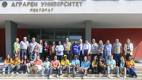 Accessibility: Group photo of people in front of a building bearing the inscription ‘Аграрен Университет Ректорат’