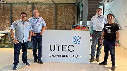 Auf dem Fußboden steht ein zwei Meter breites Schild mit dem Schirftzug "UTEC". Links davon stehen zwei Männer, ebenso wie rechts davon.