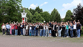 Gruppenfoto aller an den Port2Port Wettbewerben teilnehmenden Schülerinnen und Schüler. Sie stehen draußen vor einem Seezeichen.