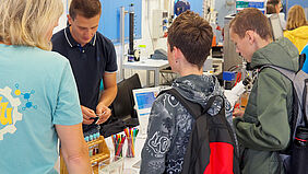 Mitarbeiter Kevin Bläsing (2.v.l.) zeigt zwei Schülern in einem Labor die Wirkungsweise der Chromatografie.